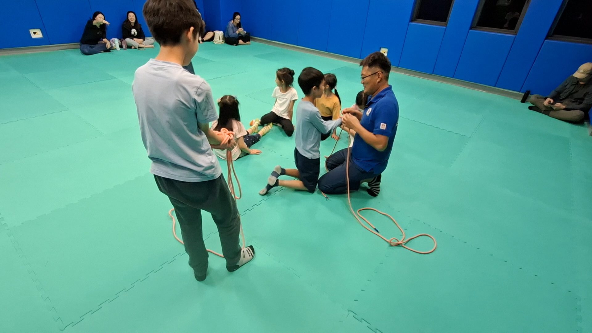 教練跪著和男孩一起拉繩子打結