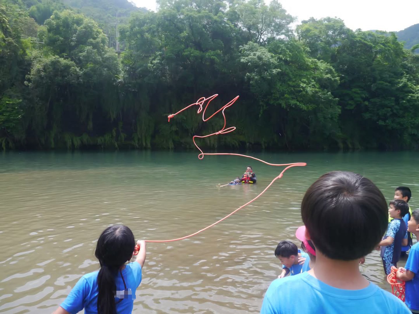 孩子在溪邊把橘色救生拋繩甩向河中央