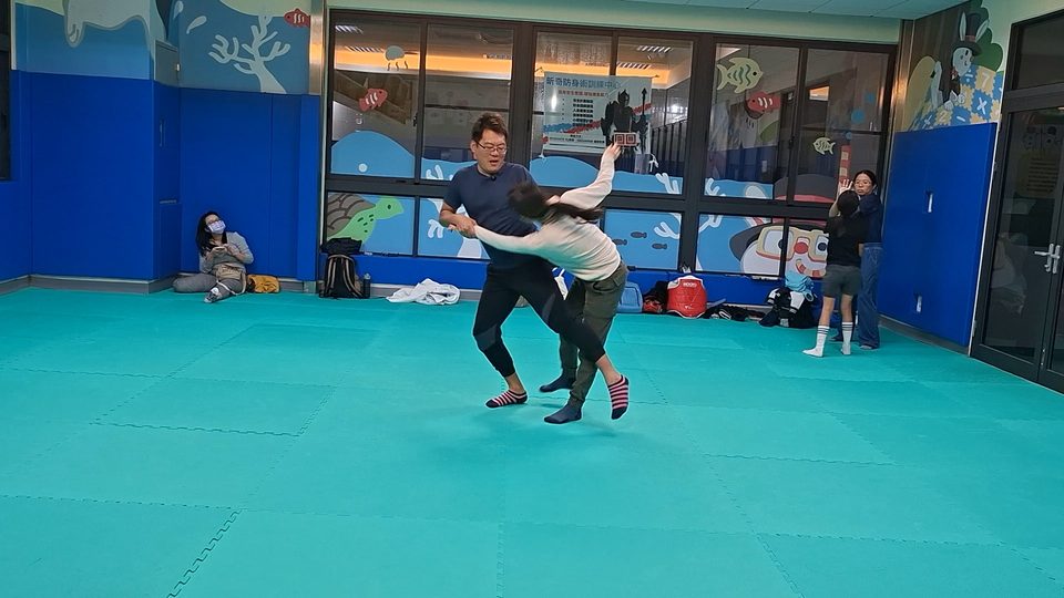 教練示範把女學員往側邊帶倒的動作